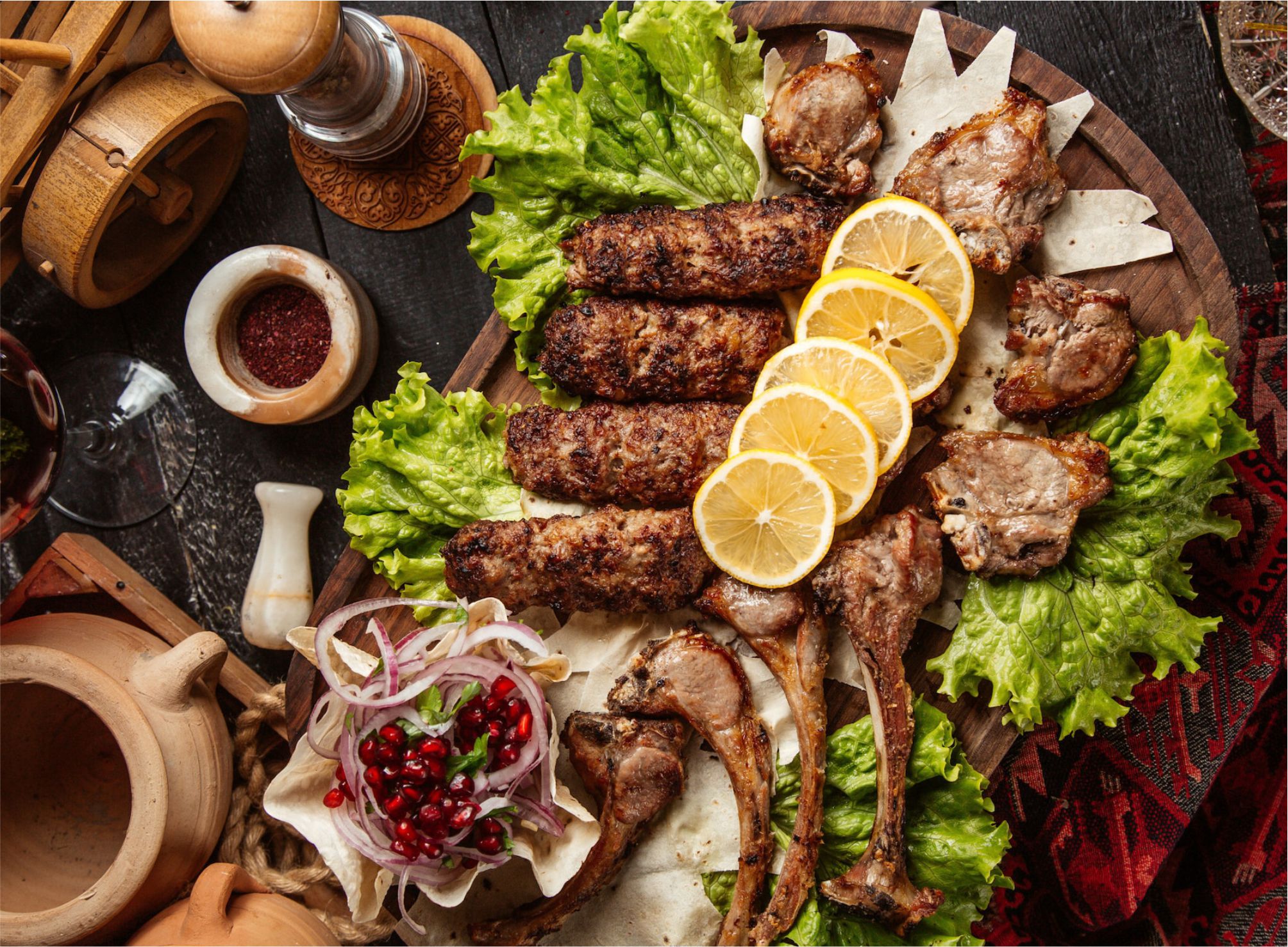 Balkan-Grillplatte mit Cevapi, Lammkoteletts, Zitrone und frischem Salat